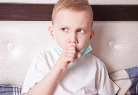 Ill boy suffering from cough in bed at home Stock Photos