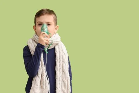 Ill little boy using nebulizer on green background Stock Photos