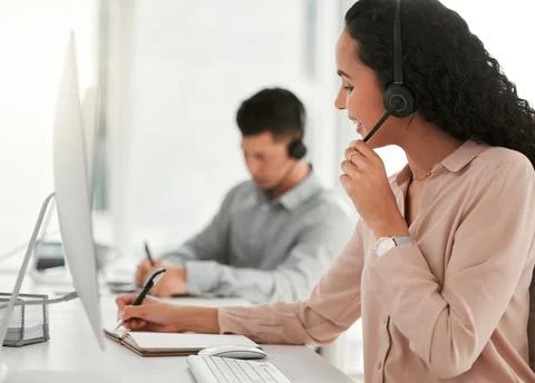 Ill make a note of that. two young call center agents working in an office. Stock Photos