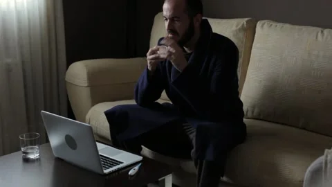 Ill man sitting on sofa during online consultation with doctor Stock Footage 148112496