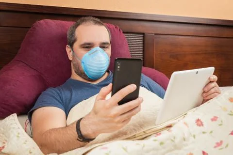 Ill man using tablet and phone in the bed. Teleworking Fotos Stock