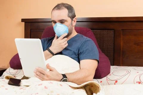 Ill man using tablet in the bed. Fotos de archivo