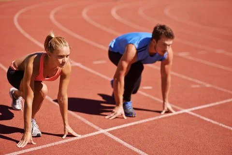 Ill take you on. Shot of two young people getting ready to race on an athletics Stock Photos
