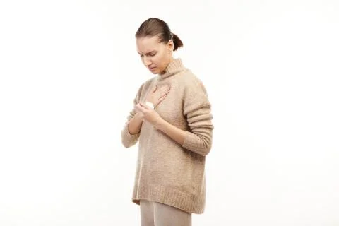 Ill woman in beige sweater has thore troat and holds a napkin. Stock Photos