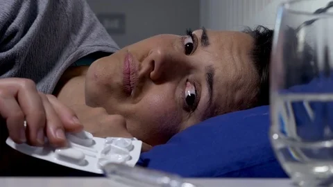 Ill woman lying in bed taking medicine closeup Stock Footage 75449161