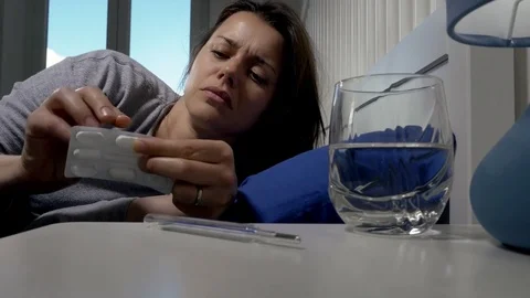 Ill woman lying in bed taking medicine Stock Footage 75450804