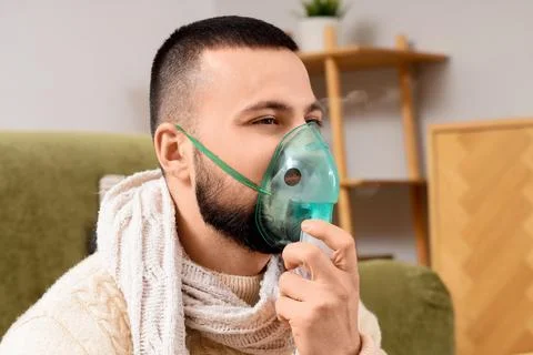 Ill young man using nebulizer at home, closeup Stock Photos