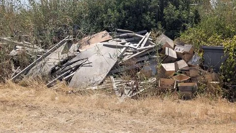 Illegal dump of building rubble and cardboard boxes in dry scrubland Photos