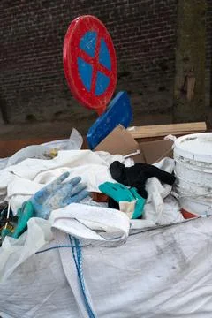 Illegal dumping near brick wall with red no parking sign, white sacks, plasti Stock Photos