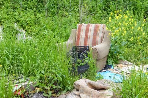 Illegal garbage dump in nature. Abandoned armchair in nature.  Environmenta.. Stock Photos