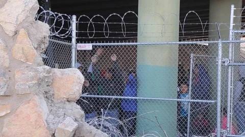 Illegal migrants looking from a barbed wire fence Stock Footage 109170577