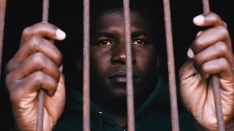 Illegal refugee - young immigrant clinging to the bars of his cell Stock Footage 240392548