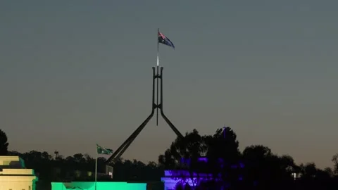 Illuminated Australian flag flapping wind atop Parliament House dusk Canberra Stock Footage 328071950