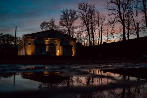 Illuminated Building at Dusk with Reflection in Puddle Stock Photos