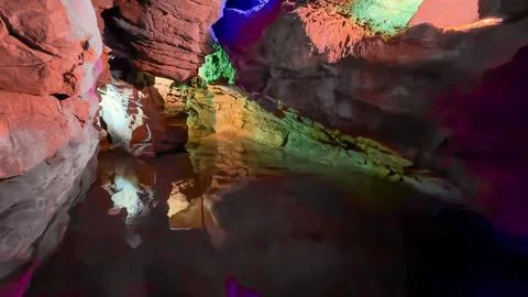 Illuminated Cave Interior with Multicolor Light Reflections on Water Stock Photos
