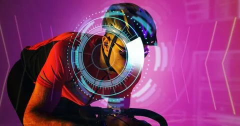 Illuminated circular pattern over caucasian male athlete riding bike over Stock Photos