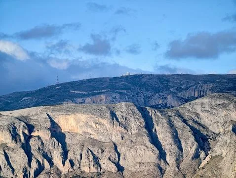 Illuminated cliffside exposing complex stratification and rugged terrain id.. Фото