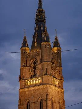 Illuminated clock tower with gothic elements in the evening, blue hour in a Stock Photos