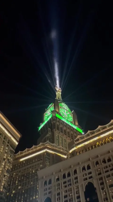 Illuminated Clock Tower with Green Lights and Bright Beam at Night in Makkah, Sa Stock Footage 323157868