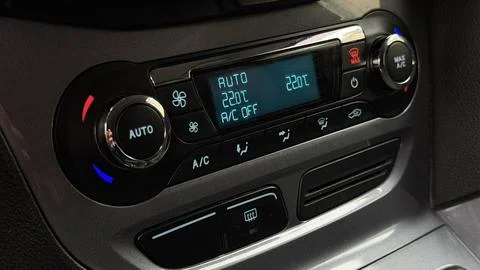 Illuminated digital climate control panel inside a modern car cabin showing Stock Photos