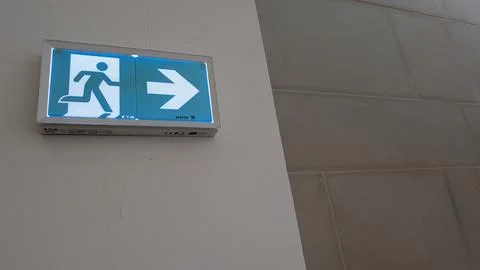 Illuminated emergency exit sign on an interior wall Stock Photos