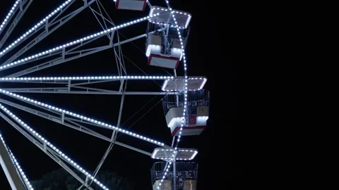 Illuminated Ferris wheel rotating at night during a winter festival Stock Footage 325790963