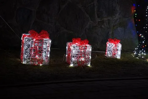 Illuminated gift boxes lit up in festive outdoor nighttime scene with stone.. Stock Photos