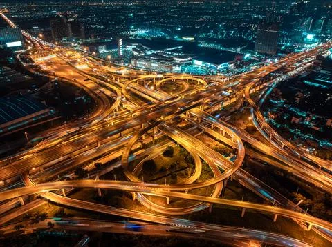 Illuminated Highway Interchange Featuring Complex Road Networks In Samut Pr.. Stock Photos