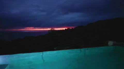 Illuminated Infinity Pool Overlooking Ocean at Dramatic Twilight with Stormy. Stock Footage 338360939