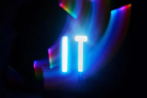 Illuminated IT. Neon IT text with vibrant light trails in the dark Stock Photos