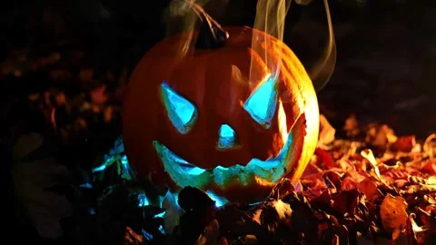 Illuminated Jack Lantern pumpkin in the dark. orange pumpkin with blue eyes Stock Footage 317954021