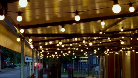 Illuminated light bulbs hanging on restaurant terrace ceiling at dusk in Stock Footage 344355371