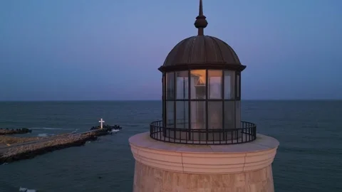 Illuminated lighthouse tower at twilight overlooking the ocean, with a glowing Video stock 301698416