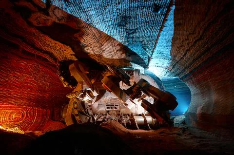 Illuminated mining drilling machine in salt quarry tunnel Stock Photos