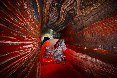 Illuminated mining drilling machine in salt quarry tunnel Stock Photos