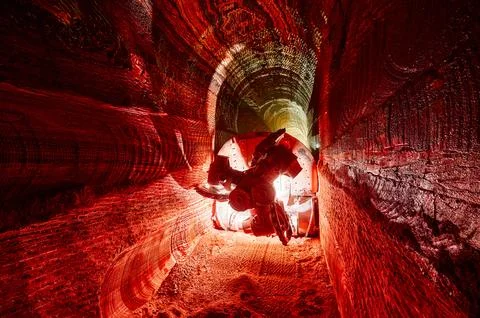 Illuminated mining drilling machine in salt quarry tunnel Stock Photos