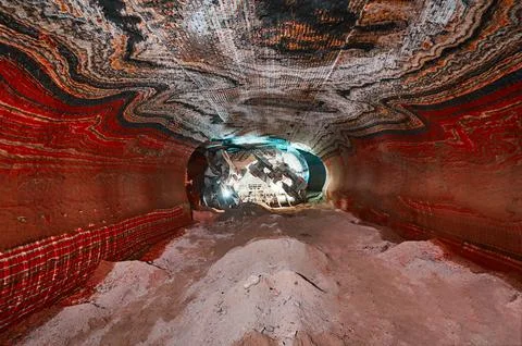 Illuminated mining drilling machine in salt quarry tunnel Stock Photos