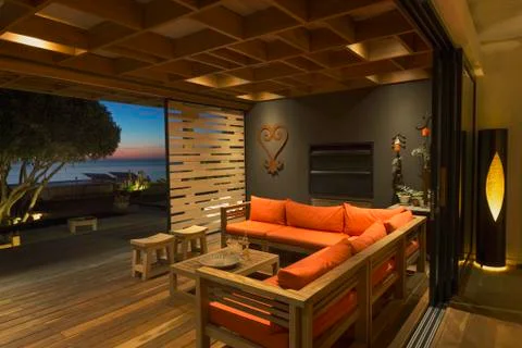 Illuminated modern, luxury home showcase sofa open to patio at dusk Stock Photos