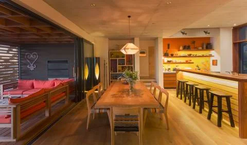 Illuminated modern, luxury home showcase interior dining room open to patio Stock Photos