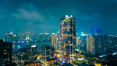 Illuminated modern skyscraper towering over the dense urban cityscape and Stock Footage 327372259