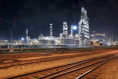 Illuminated oil refinery at night with rail tracks on foreground, Stock Photos
