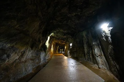 Illuminated path through a rugged underground stone tunnel Stock Photos