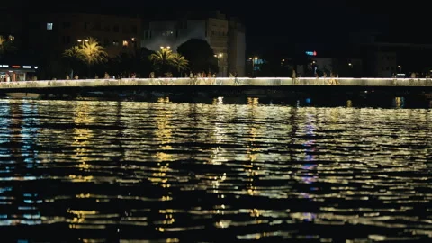 Illuminated Pedestrian Bridge Over Waterfront at Night Vídeo Stock 340455937