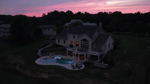 Illuminated pool glows beside darkened luxury home at dusk in United States Stock Footage 342577010