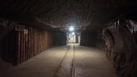 Illuminated rail tunnel with mining tracks and rock salt walls in the Wieliczka Stock Footage 334720718
