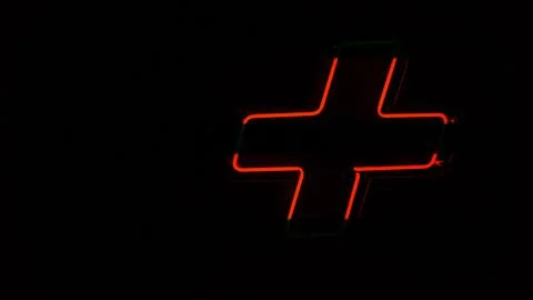 Illuminated red neon light, plus symbol on the wall Stock Photos
