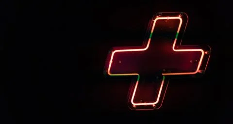 Illuminated red neon light, plus symbol on the wall Stock Photos