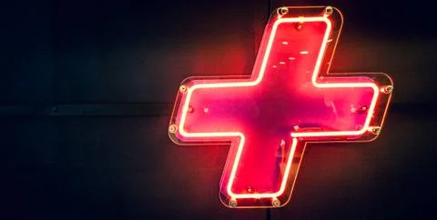 Illuminated red neon light, plus symbol on the wall Stock Photos