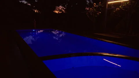Illuminated Resort Swimming Pool With Deep Blue Underwater Lights Reflecting Tro Stock Footage 336699322