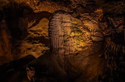 Illuminated rock formations glow within a dark cave interior. Stock Photos